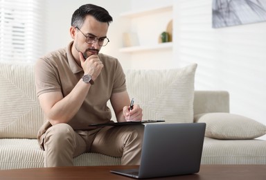 Photo of Professional psychologist having online consultation with his client via laptop on sofa indoors. Space for text