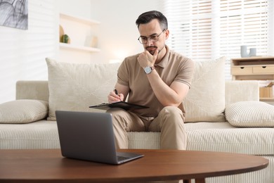 Photo of Professional psychologist having online consultation with his client via laptop on sofa indoors