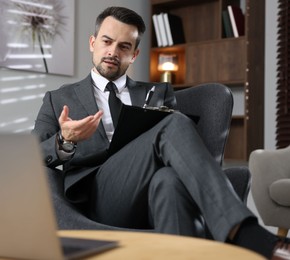 Photo of Professional psychologist having online consultation with his client via laptop indoors