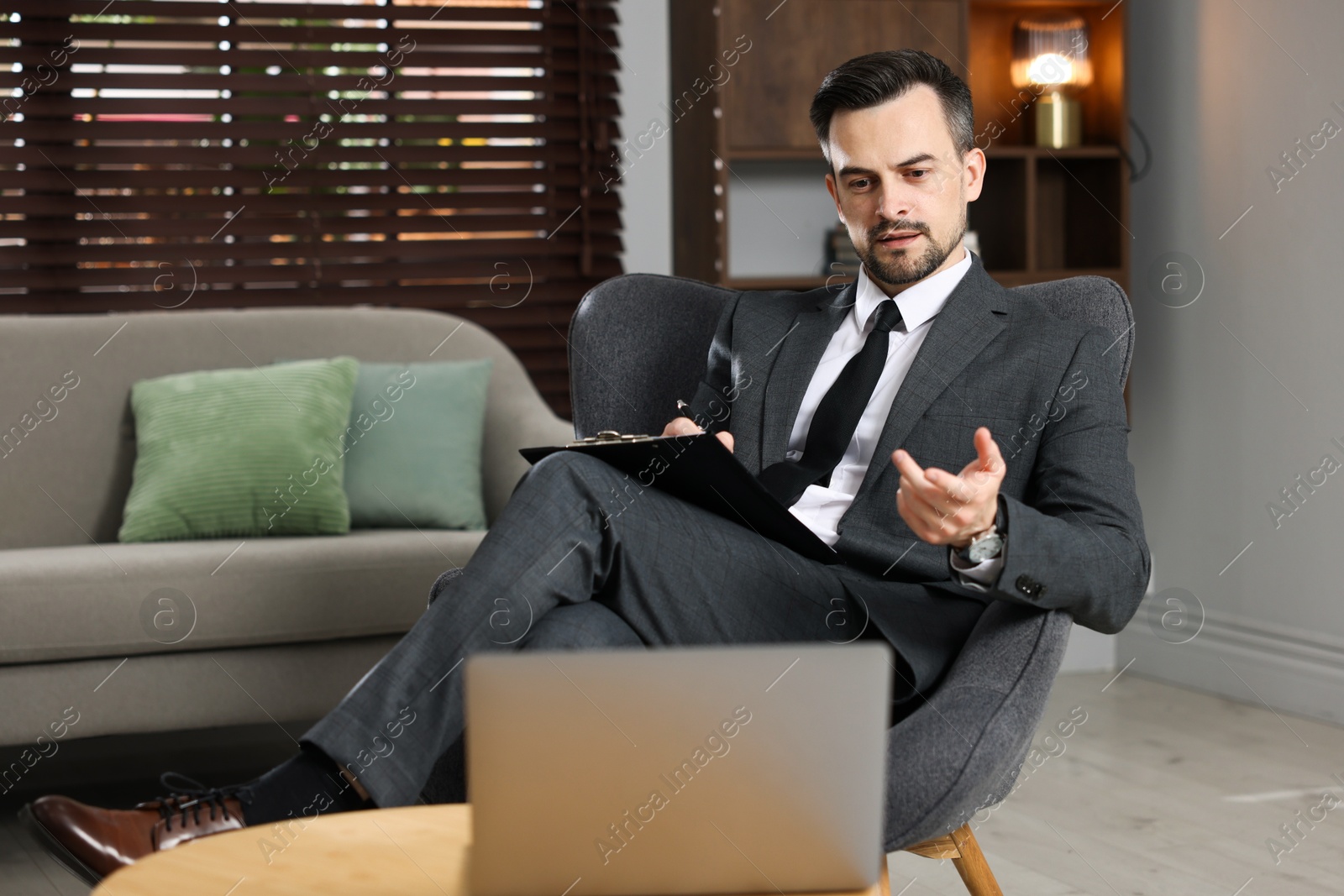 Photo of Professional psychologist having online consultation with his client via laptop indoors