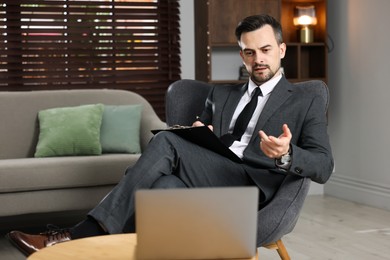 Photo of Professional psychologist having online consultation with his client via laptop indoors