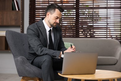 Photo of Professional psychologist having online consultation with his client via laptop indoors