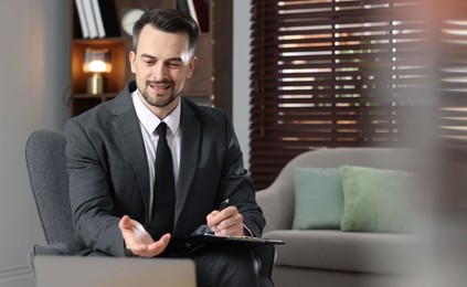 Photo of Professional psychologist with clipboard in his office. Space for text