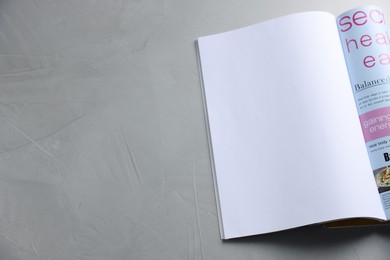 Photo of Open magazine on light grey table. Mockup for design