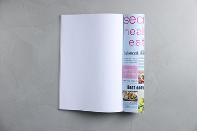 Photo of Open magazine on light grey table, top view. Mockup for design