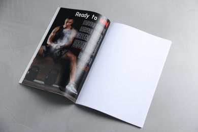 Photo of Open magazine on light grey table. Mockup for design
