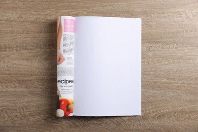 Photo of Open magazine on wooden table, top view. Mockup for design