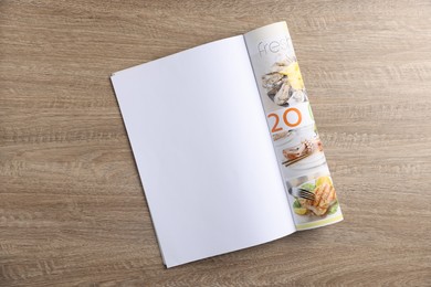 Photo of Open magazine on wooden table, top view. Mockup for design