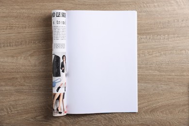 Photo of Open magazine on wooden table, top view. Mockup for design