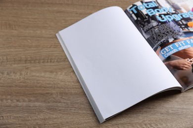 Photo of Open magazine on wooden table. Mockup for design