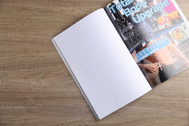 Photo of Open magazine on wooden table, top view. Mockup for design