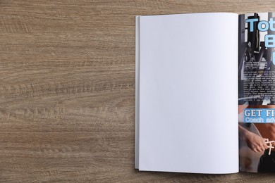 Photo of Open magazine on wooden table, top view. Mockup for design