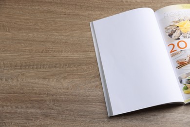 Photo of Open magazine on wooden table. Mockup for design