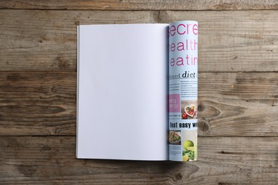 Photo of Open magazine on wooden table, top view. Mockup for design