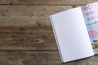 Photo of Open magazine on wooden table, top view. Mockup for design