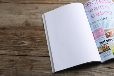 Photo of Open magazine on wooden table. Mockup for design