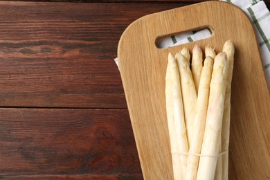 Photo of Raw asparagus spears on wooden table, top view. Space for text