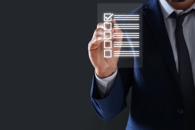 Image of Businessman putting tick in check list on virtual screen against dark grey background, closeup