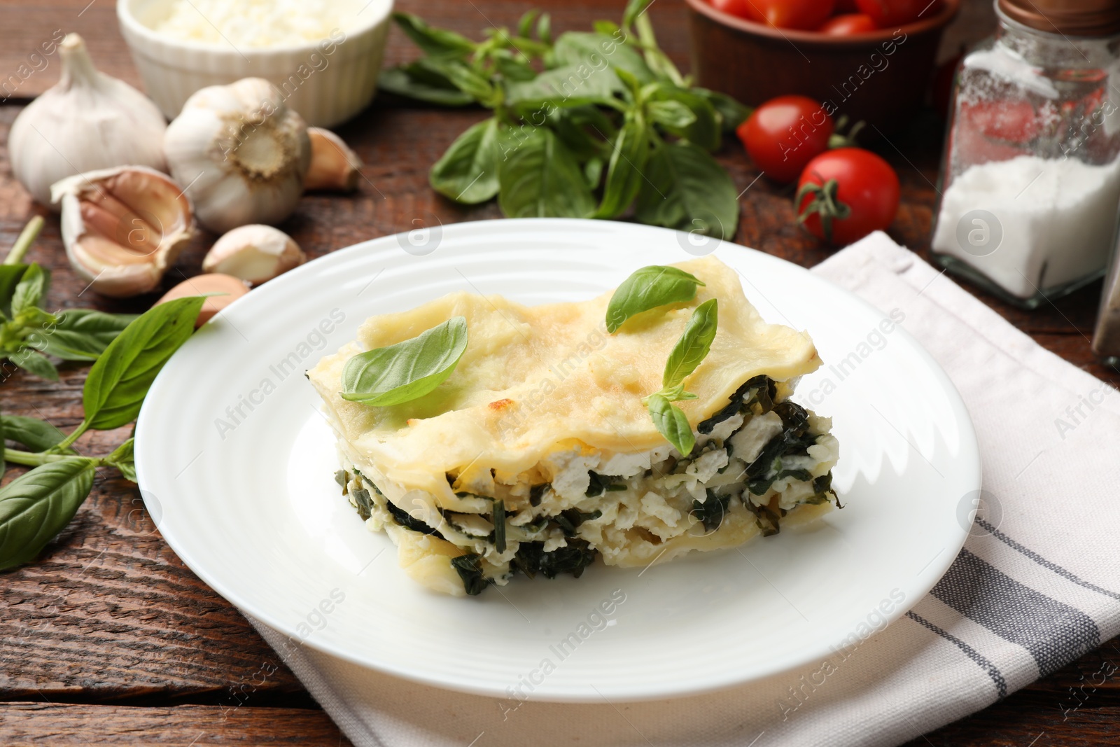 Piece of tasty vegetarian lasagna and ingredients on wooden table, closeup Photo of Piece of tasty vegetarian lasagna and ingredients on wooden table, closeup