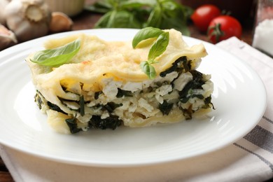 Photo of Piece of tasty vegetarian lasagna and ingredients on table, closeup