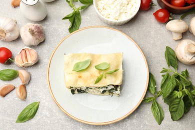 Photo of Piece of tasty vegetarian lasagna and ingredients on grey table, flat lay