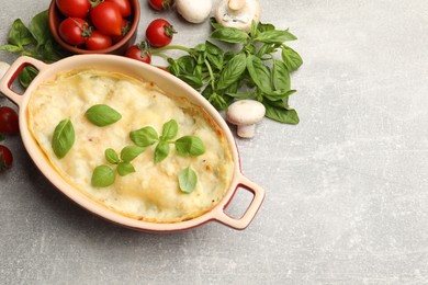 Photo of Tasty vegetarian lasagna and ingredients on grey table, flat lay. Space for text