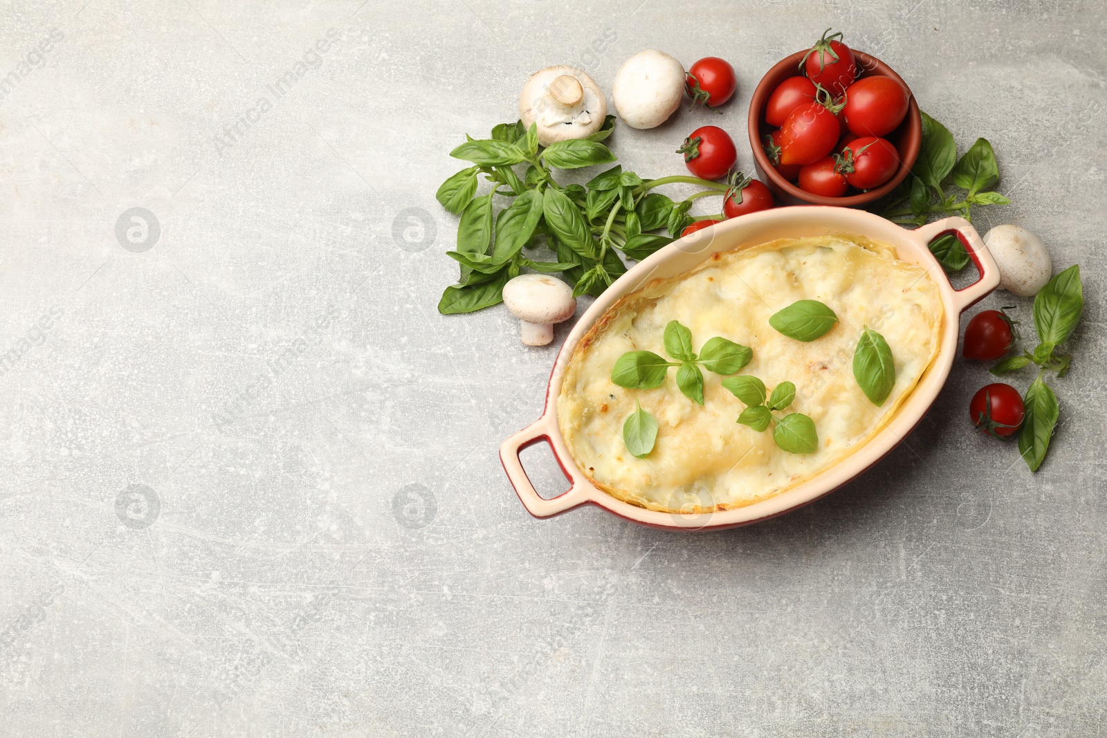 Photo of Tasty vegetarian lasagna and ingredients on grey table, flat lay. Space for text