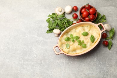 Photo of Tasty vegetarian lasagna and ingredients on grey table, flat lay. Space for text