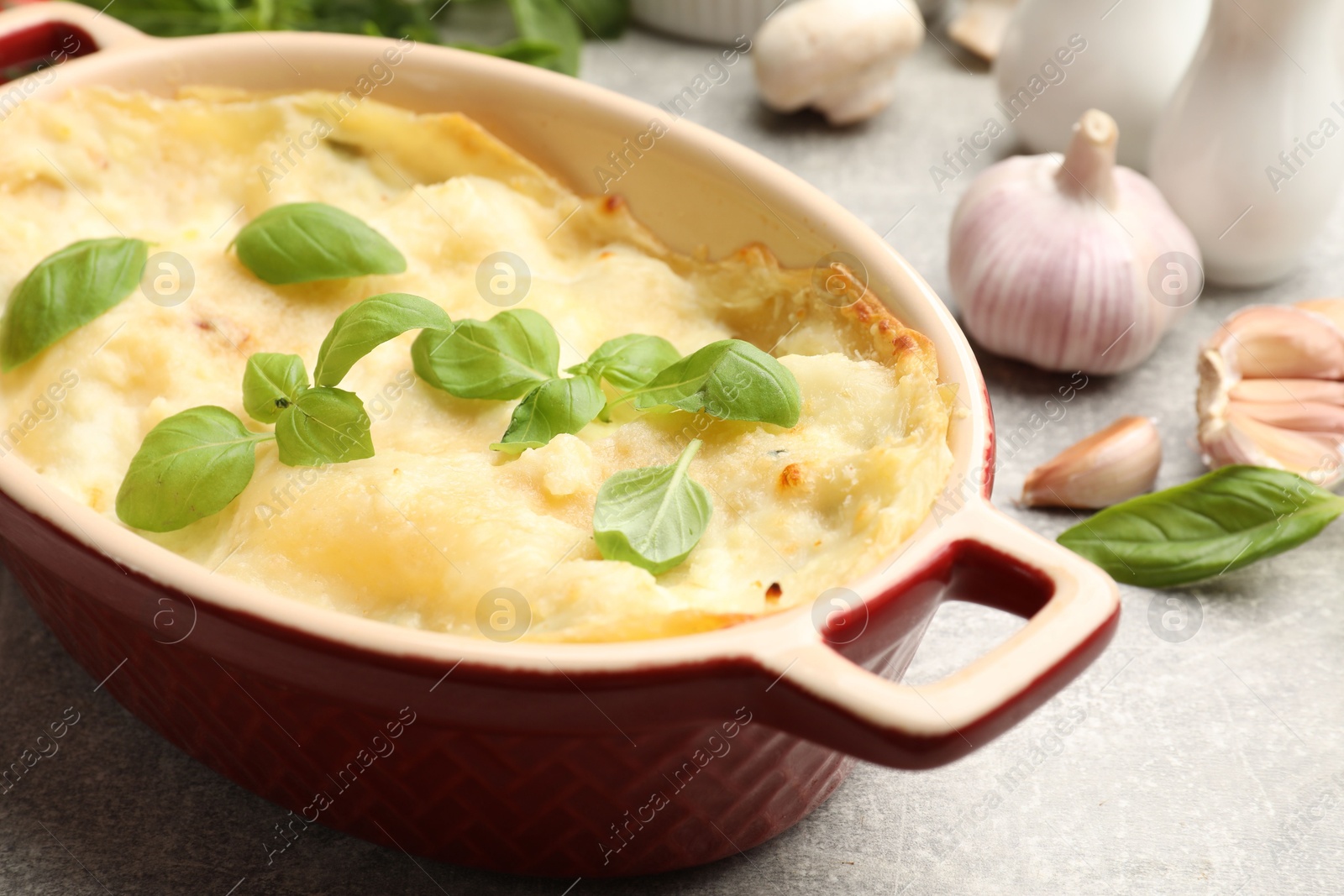 Tasty vegetarian lasagna and ingredients on grey table, closeup Photo of Tasty vegetarian lasagna and ingredients on grey table, closeup