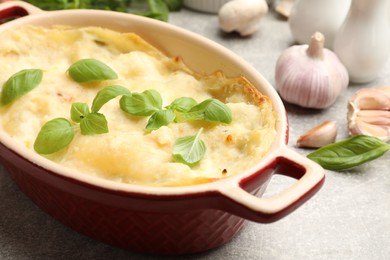 Photo of Tasty vegetarian lasagna and ingredients on grey table, closeup