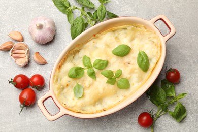 Photo of Tasty vegetarian lasagna and ingredients on grey table, flat lay