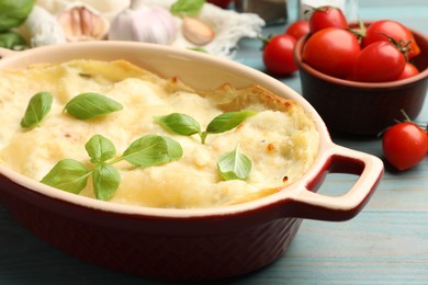 Photo of Tasty vegetarian lasagna and ingredients on light blue wooden table, closeup