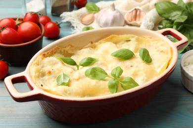 Photo of Tasty vegetarian lasagna and ingredients on light blue wooden table, closeup
