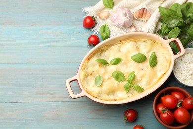 Photo of Tasty vegetarian lasagna and ingredients on light blue wooden table, flat lay. Space for text