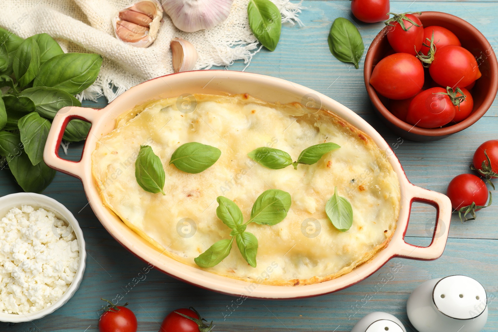 Tasty vegetarian lasagna and ingredients on light blue wooden table, flat lay Photo of Tasty vegetarian lasagna and ingredients on light blue wooden table, flat lay