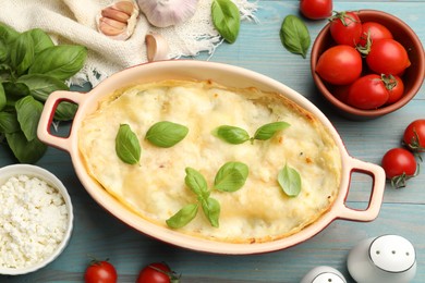 Photo of Tasty vegetarian lasagna and ingredients on light blue wooden table, flat lay