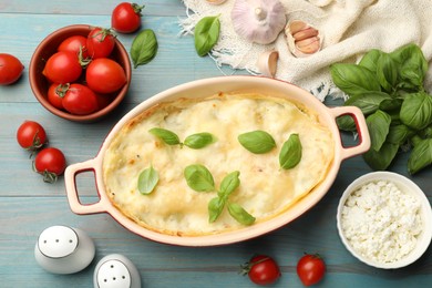 Photo of Tasty vegetarian lasagna and ingredients on light blue wooden table, flat lay