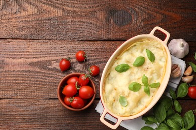 Photo of Tasty vegetarian lasagna and ingredients on wooden table, flat lay. Space for text
