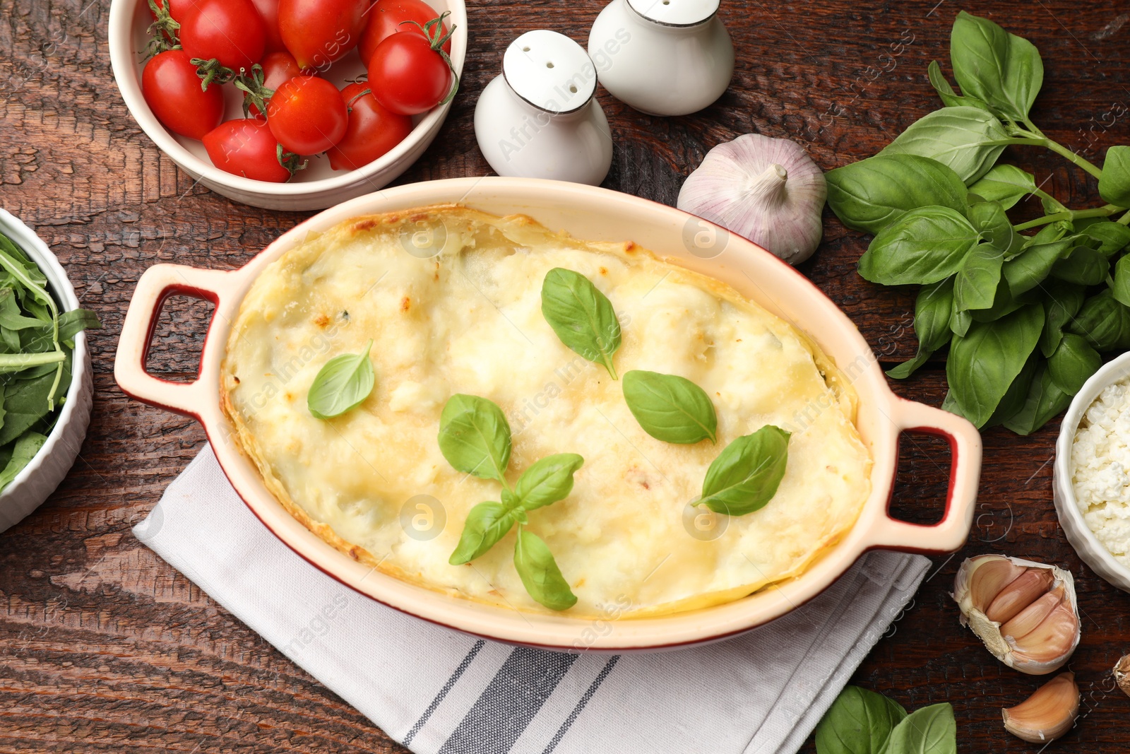 Photo of Tasty vegetarian lasagna and ingredients on wooden table, flat lay