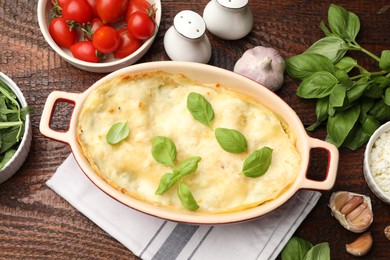 Photo of Tasty vegetarian lasagna and ingredients on wooden table, flat lay