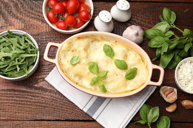 Photo of Tasty vegetarian lasagna and ingredients on wooden table, flat lay