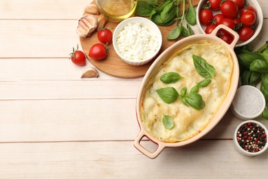 Photo of Tasty vegetarian lasagna and ingredients on wooden table, flat lay. Space for text