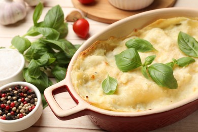 Photo of Tasty vegetarian lasagna and ingredients on wooden table, closeup