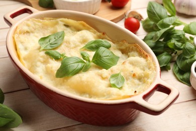 Photo of Tasty vegetarian lasagna and ingredients on wooden table, closeup