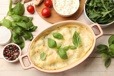 Photo of Tasty vegetarian lasagna and ingredients on wooden table, flat lay