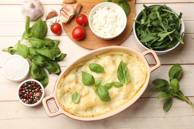 Photo of Tasty vegetarian lasagna and ingredients on wooden table, flat lay