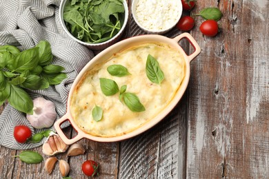 Photo of Tasty vegetarian lasagna and ingredients on wooden table, flat lay. Space for text