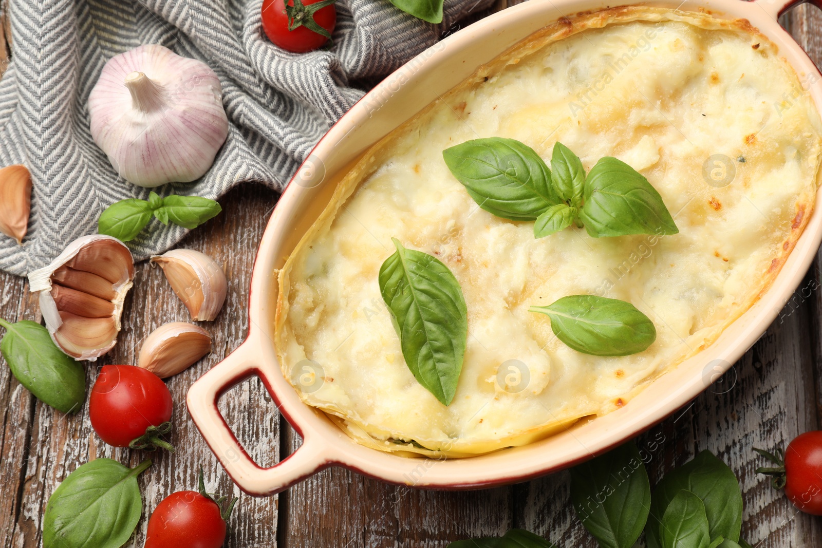 Photo of Tasty vegetarian lasagna and ingredients on wooden table, flat lay