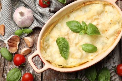 Photo of Tasty vegetarian lasagna and ingredients on wooden table, flat lay