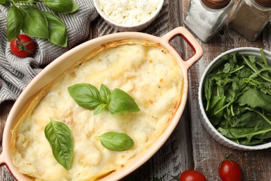 Photo of Tasty vegetarian lasagna and ingredients on wooden table, flat lay